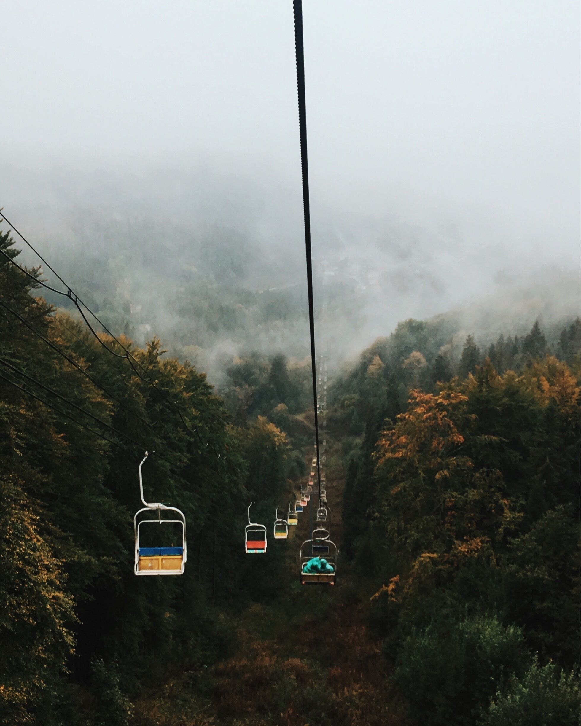 A cable car system in a forested area with mist.