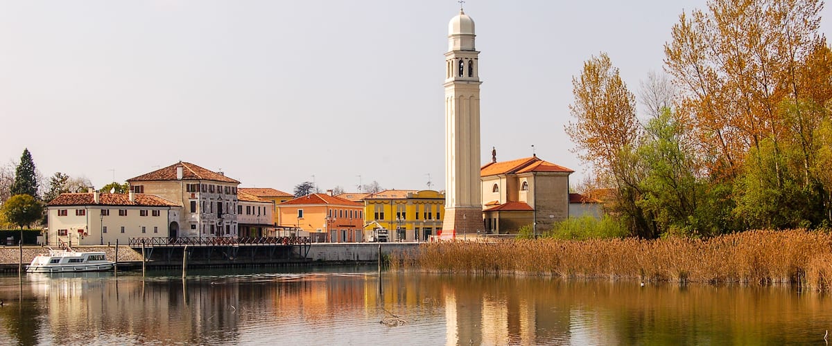 A river with a bridge, a tall tower, and buildings along the riverbank.