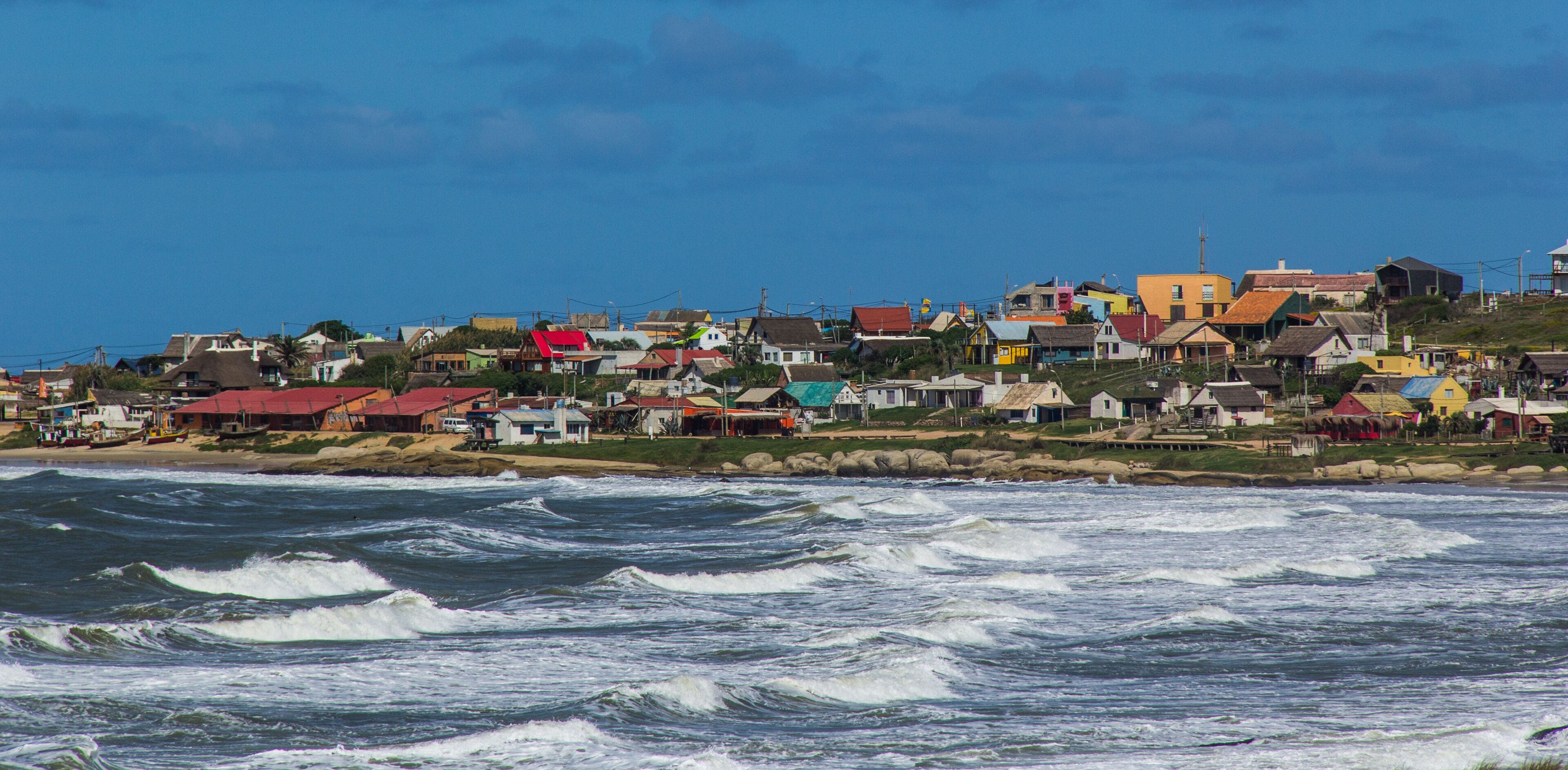 A coastal town with colorful houses and waves crashing onto the shore.