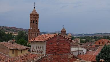 A historic town with a prominent bell tower and red-tiled rooftops.