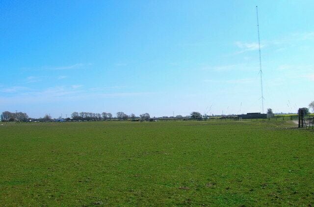 A wide-open field with a tall communication tower in the distance.