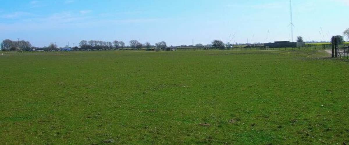 A wide-open field with a tall communication tower in the distance.
