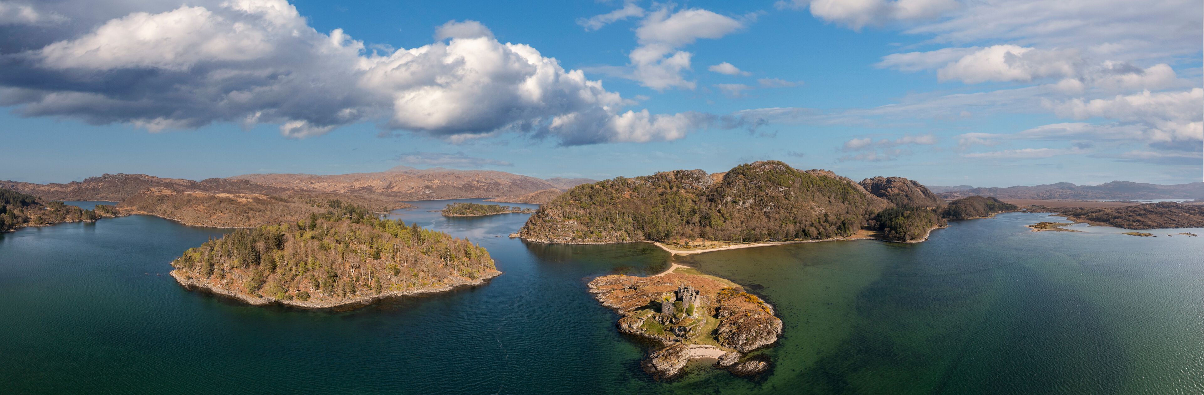 A lake surrounded by forested islands and distant mountains.
