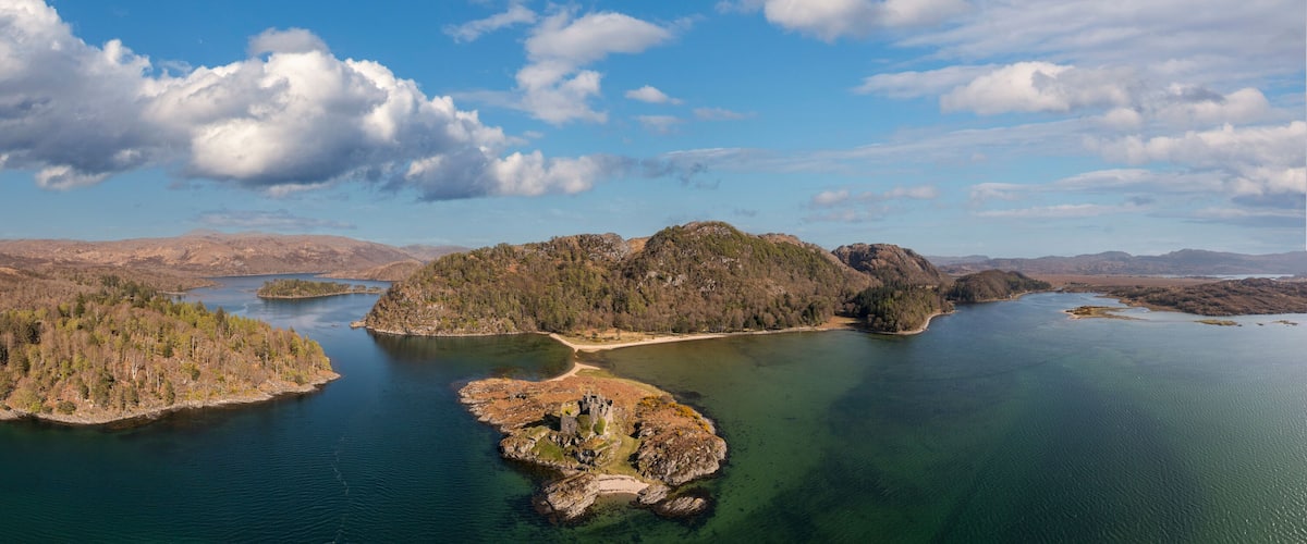 A lake surrounded by forested islands and distant mountains.
