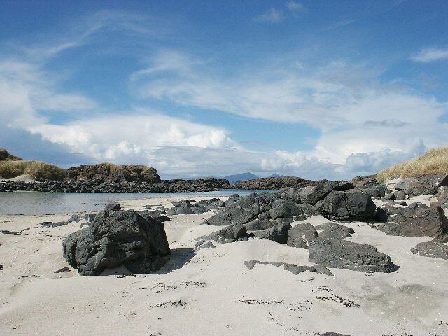 A rocky beach with large boulders and a clear sky.