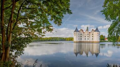 Un castillo en un lago rodeado de árboles.