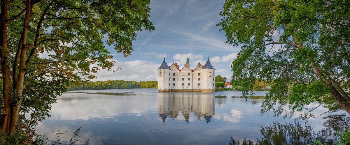 A castle on a lake surrounded by trees.