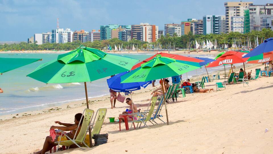 Une plage avec des parasols aux couleurs vives, des gens qui se détendent et, en arrière-plan, le profil d’une ville.