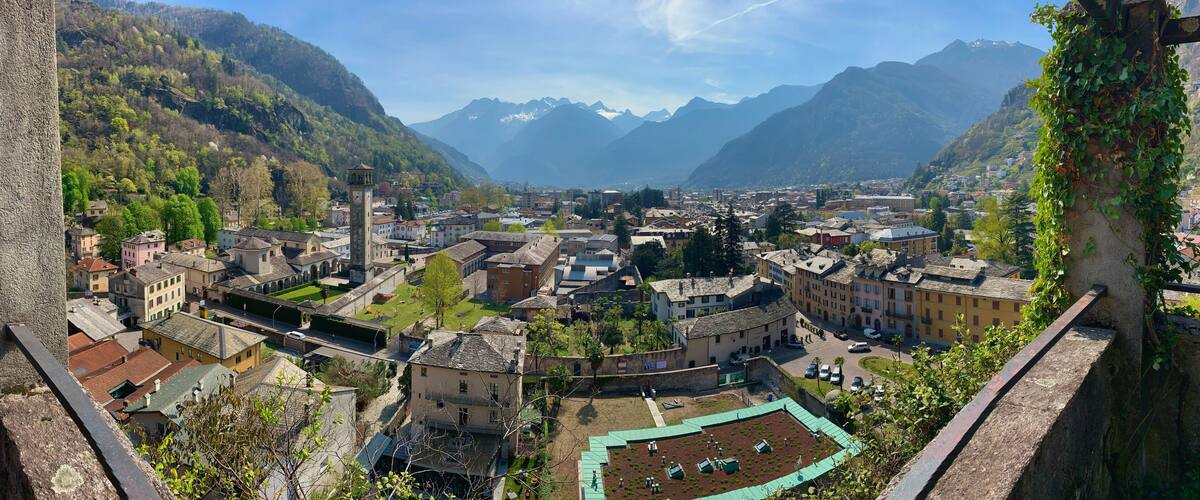 A mountainous town with historic buildings, a central square, and a prominent clock tower.