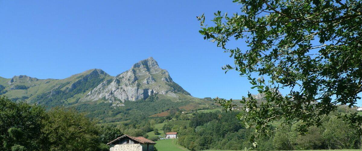 A grassy field with a stone building and a mountain in the background.