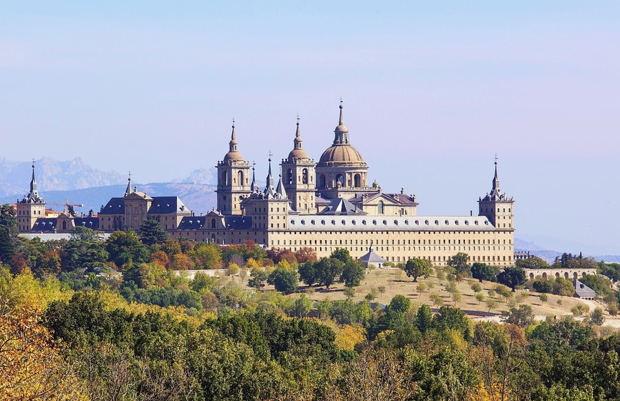 El Escorial was built by King Philip II in the late 16th century to serve as both a royal palace and as the seat of the Catholic Church in Spain. In addition to the palace the complex includes a basilica, a convent, a school, a library, and a pantheon.
While El Escorial is impressive from the outside, we actually found it a little austere on the inside. In many ways it felt more like a fine art museum than a typically elaborate European palace (such as Versailles). That said, there are some impressive sights, including works by El Greco, Bernini, and Giardini. The library was also quite beautiful, with richly carved wood shelves, a marble floor, and a colorful fresco ceiling by Pellegrino Tibaldi.
For me, the highlight of the tour was the 180ft long (55m) Hall of Battles – a barrel-vaulted room where the walls were completely covered in frescos depicting Spain's military victories over the Moors and the French. All aspects of the battle field were portrayed (when you have 180ft, that is quite doable), and the artist employed an interesting trick whereby the more distant, smaller scenes were less saturated, and the background mountains and landscape were set in hues of blue.
Overall I'd say El Escorial is worth a visit, but you probably won't need more than a couple of hours to enjoy it.