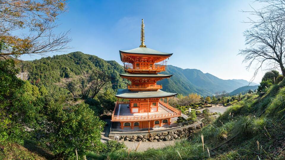 A multi-tiered pagoda surrounded by lush greenery and mountains.