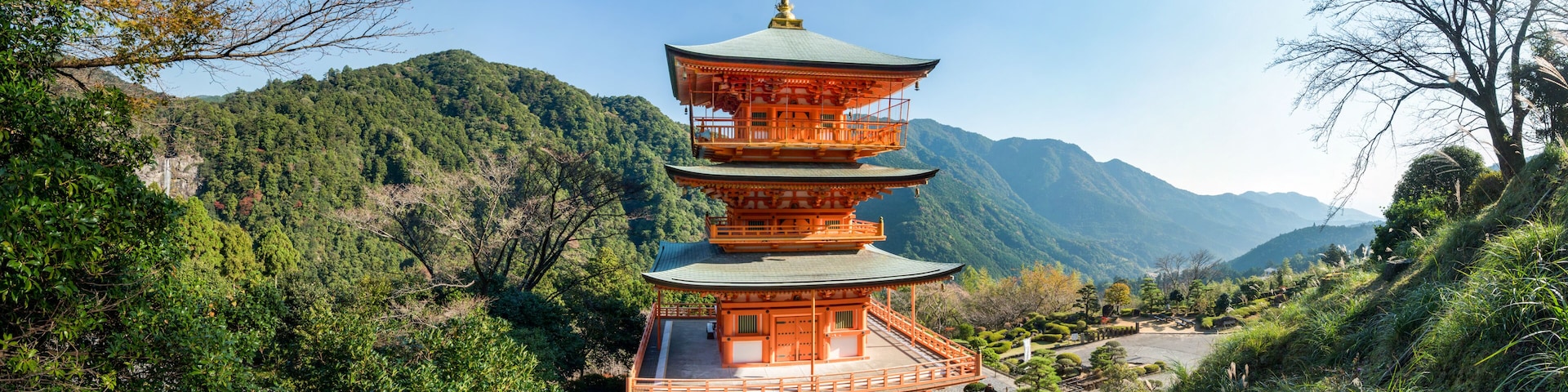 Un pagodas de varios niveles rodeado de vegetación exuberante y montañas.