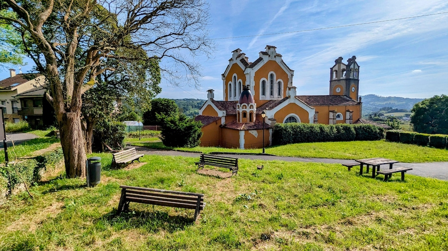 A church with a bell tower, surrounded by grass and trees.