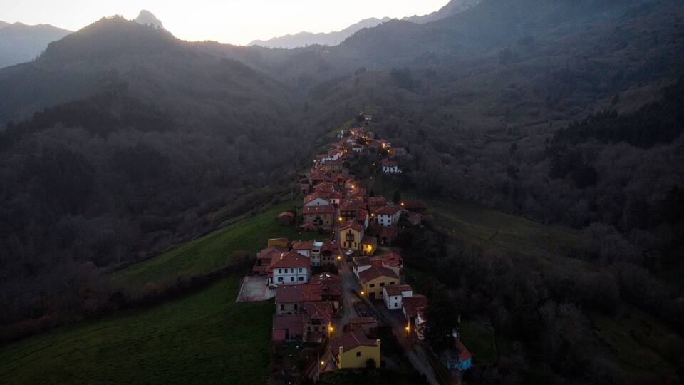 A village nestled in a valley with a winding road through it.