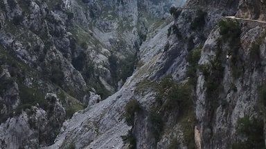 Un paisaje montañoso escarpado con riscos pronunciados y un sendero estrecho serpenteando por el valle.