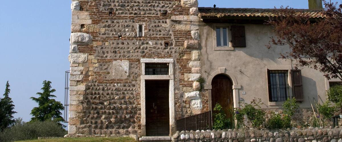 A tall clock tower with Roman numerals and a stone facade.