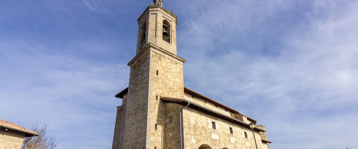 A historic stone church with a bell tower and arched windows.