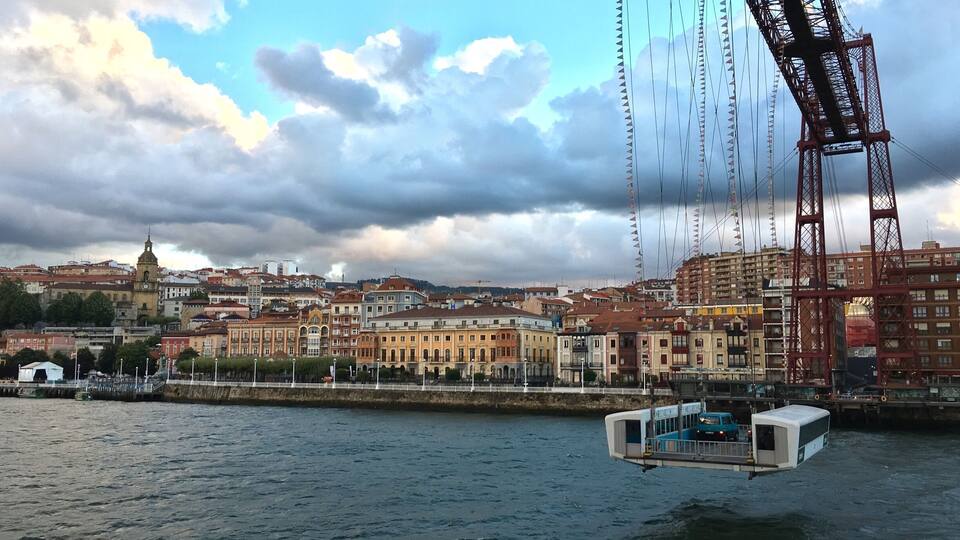 A river with a bridge, buildings, and a boat.