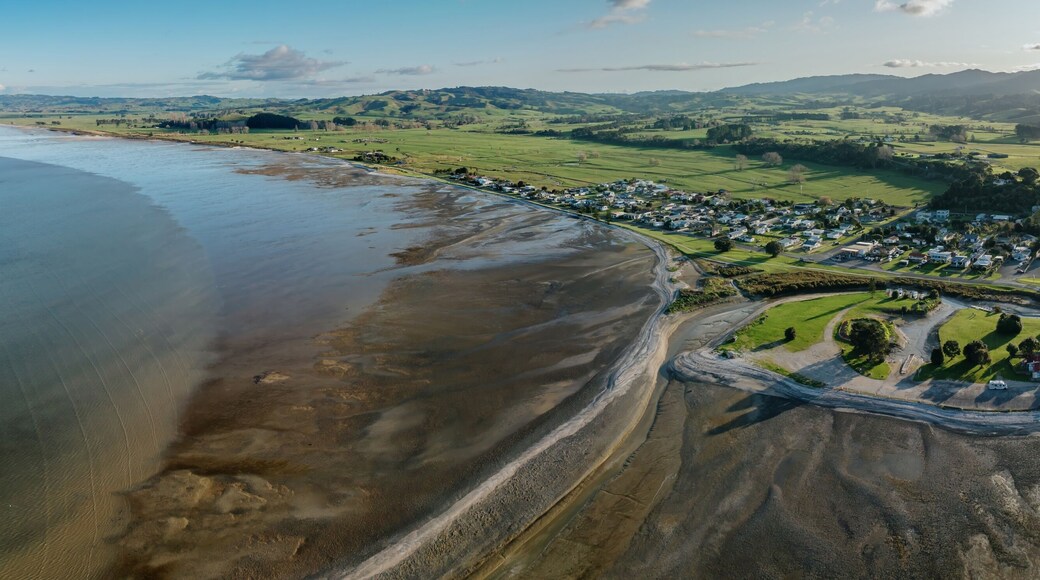 A coastal town with a beach, green fields, and rolling hills in the background.