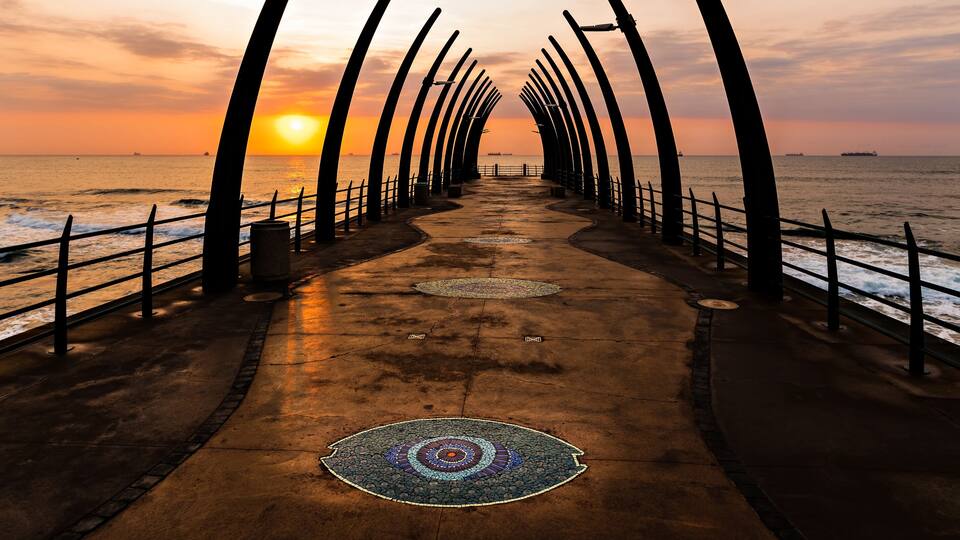 Um cais ao pôr do sol com um passeio e guarda-corpos estampados.