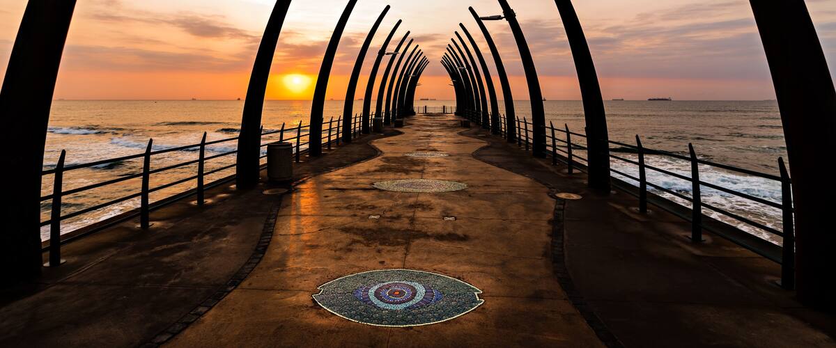 A pier at sunset with a patterned walkway and railings.