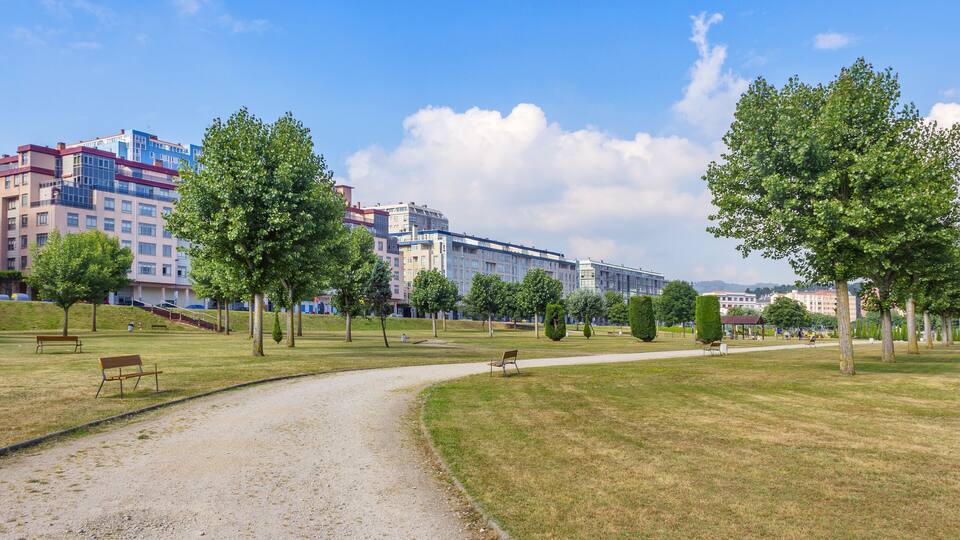 A park with a gravel path, benches, and trees.
