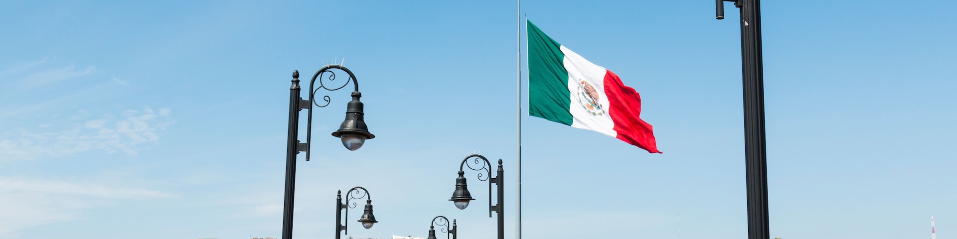 Pedestrian bridge leading to the marina and waterfront shops in Ensenada, Mexico, with a giant flag of Mexico.
