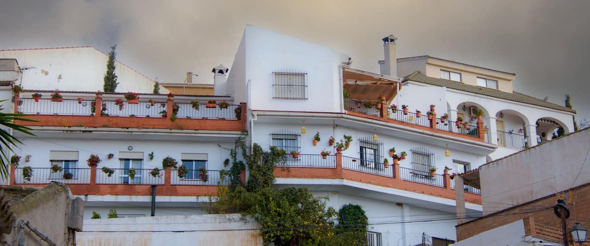 A white building with balconies adorned with potted plants and flowers.