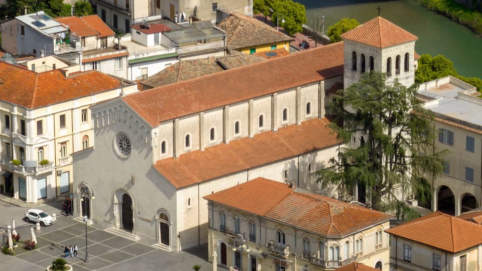 An aerial view of a historic town with a prominent church featuring a large rose window and a bell tower.
