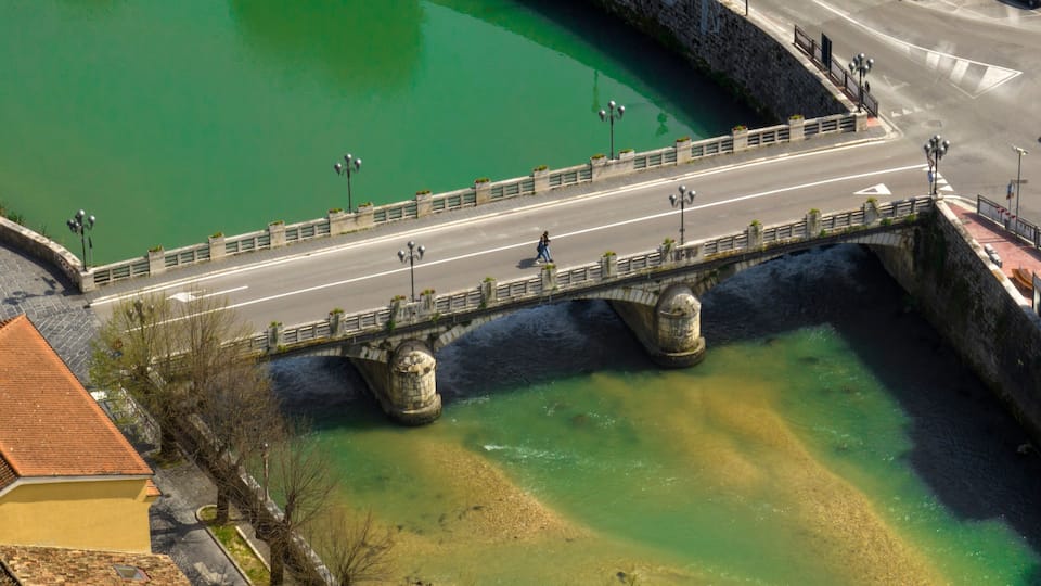 A stone bridge over a river with green water.