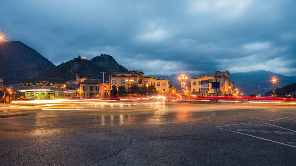 A nighttime cityscape with a mountain in the background.