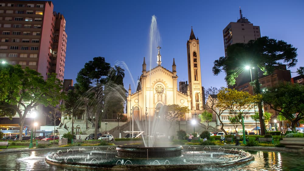 A church with a tall bell tower and a fountain in the foreground.