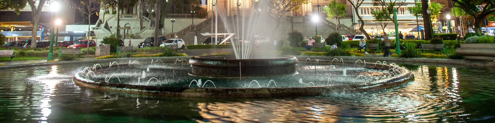 A church with a tall bell tower and a fountain in the foreground.
