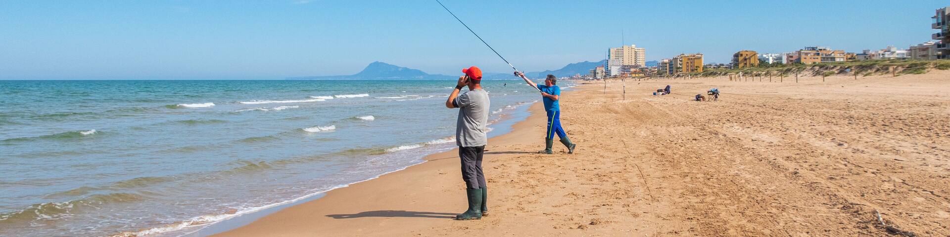 Fisherman throwing the fishing rod, on a beach at sunset, with the Mediterranean sea calm.