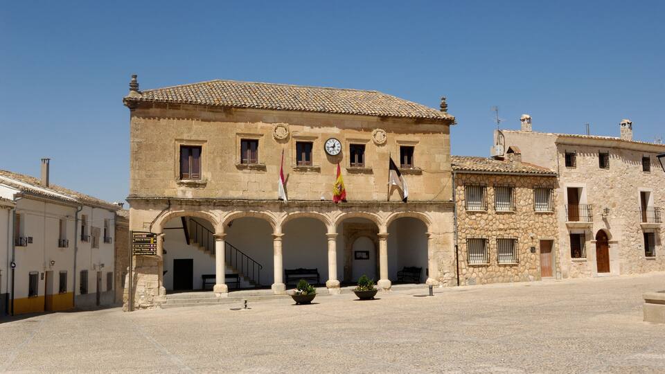 A historic building with a clock, arches, and flags.