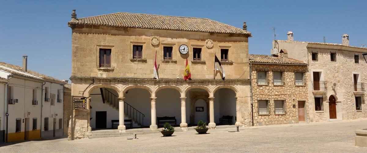 A historic building with a clock, arches, and flags.