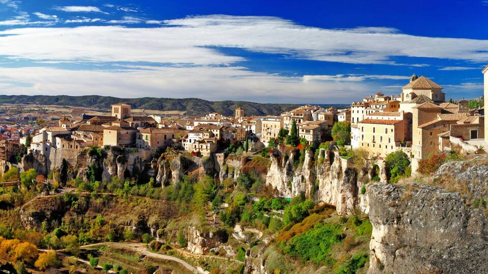 A town built on rocky cliffs with historic buildings and a clear blue sky.