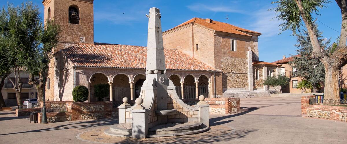 A historic building with a bell tower and a courtyard with a fountain.