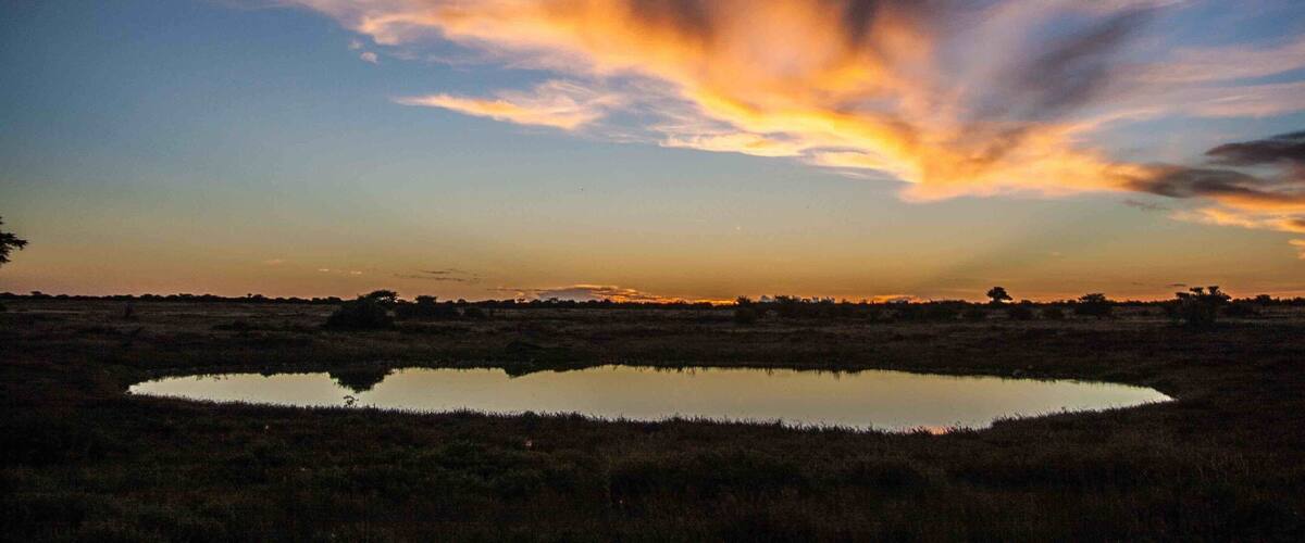 A sunset over a wetland with a reflective water body.