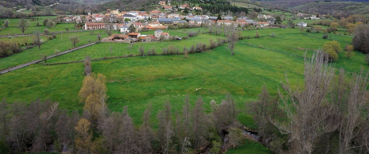 A village nestled in a valley with green fields and scattered houses.