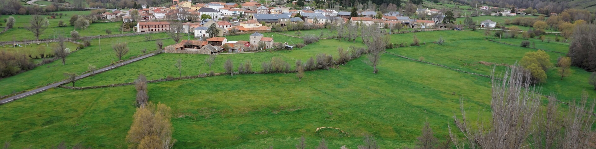 A village nestled in a valley with green fields and scattered houses.