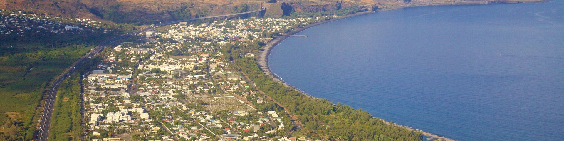 Vista aérea de un pueblo costero con una carretera curva, un puente y una extensa masa de agua.