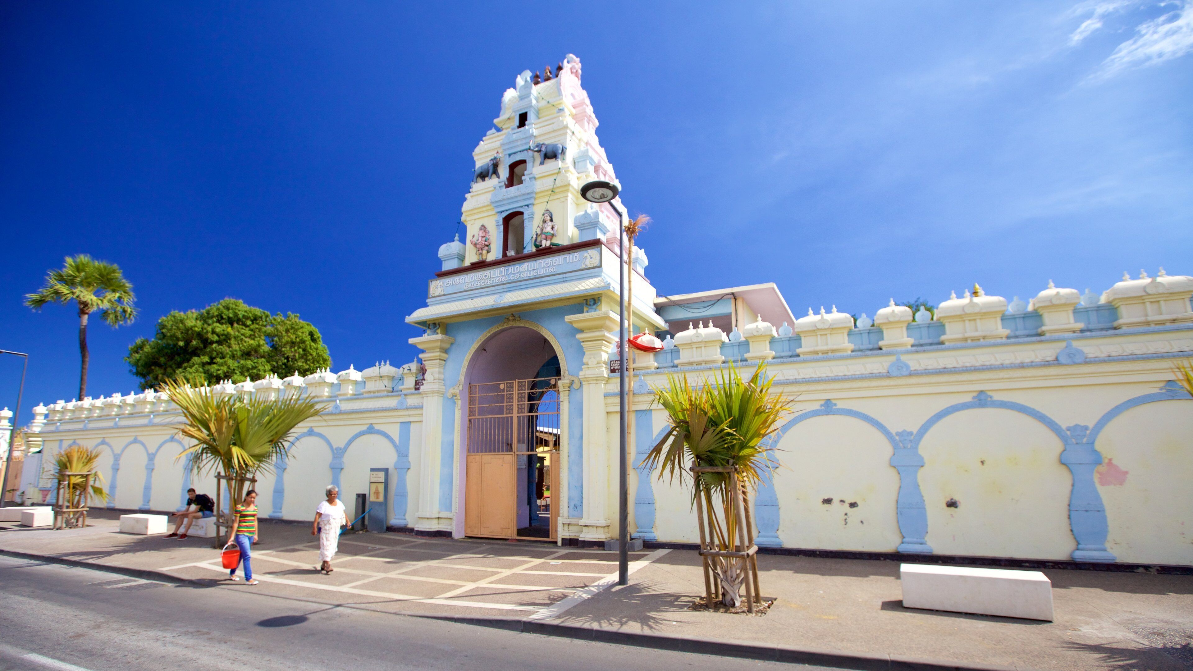 A historic building with a bell tower, palm trees, and a clear blue sky.
