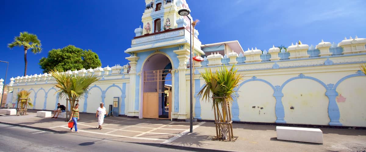 A historic building with a bell tower, palm trees, and a clear blue sky.