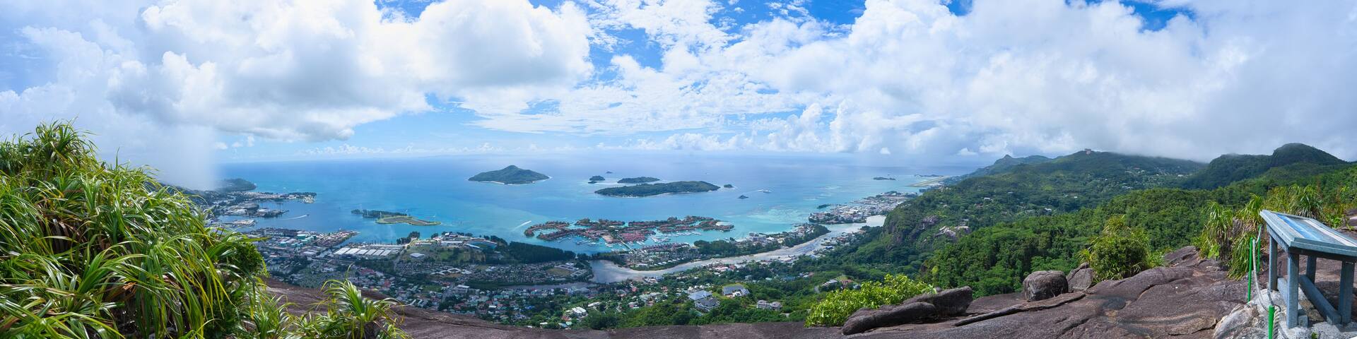 A coastal landscape with a view of the ocean, islands, and a mountainous backdrop.