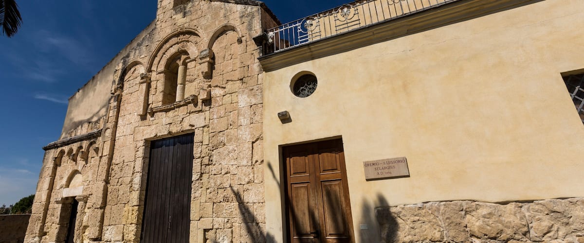 An old stone building with a wooden door and a metal balcony.