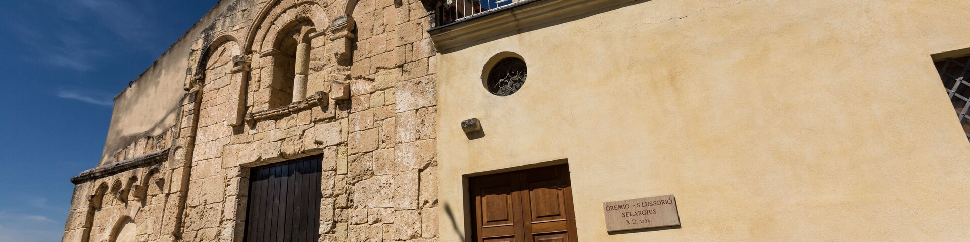 An old stone building with a wooden door and a metal balcony.