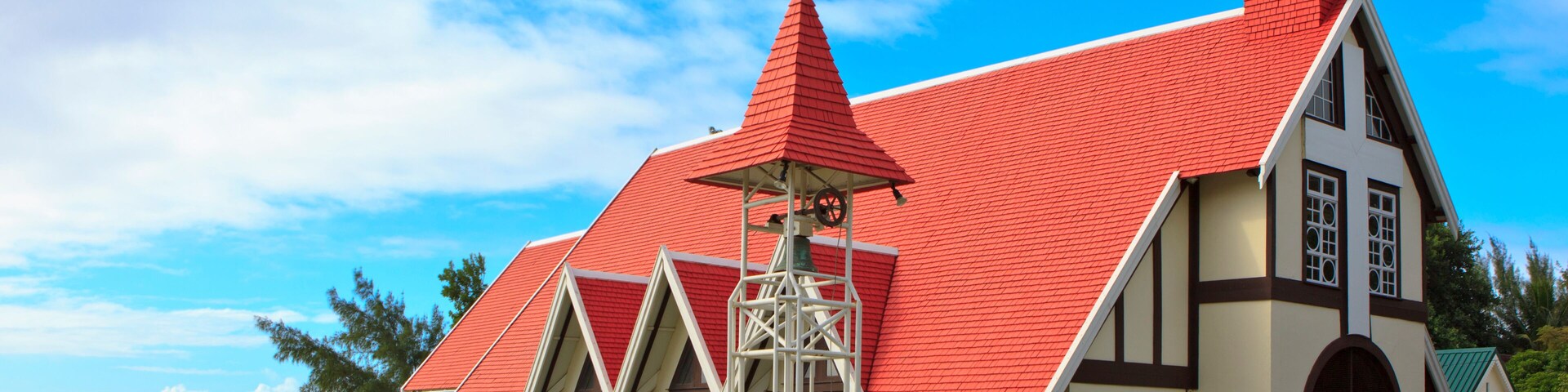A church with a red roof and white walls by the sea.