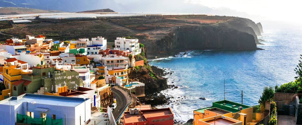 A coastal town with colorful buildings, a steep cliff, and the ocean.